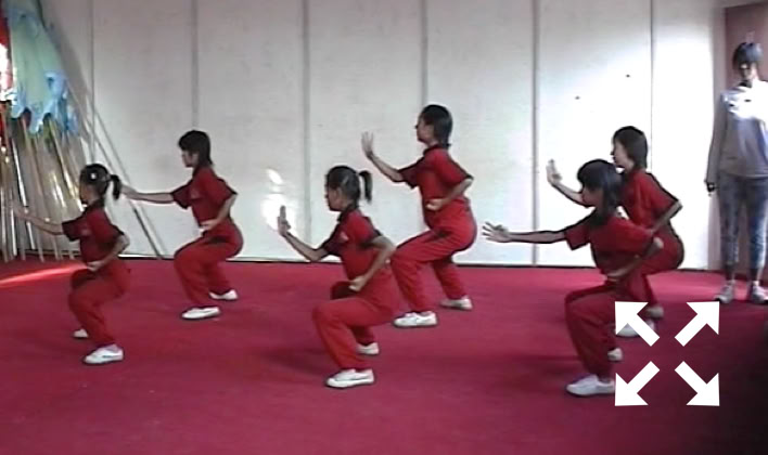 Six pratiquantes en tenue rouge effectuent des mouvements synchronisés sur un tapis rouge, à Shaolin